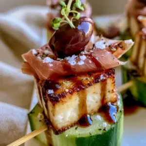 Close up handheld photo of healthy appetizers with golden charred feta and balsamic drizzle.