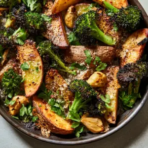 Top-down photo of roasted parmesan potatoes and broccoli showing deep golden-brown edges and vibrant green singed broccoli tips.